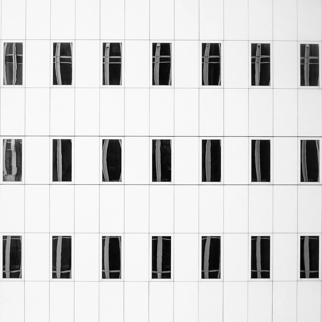 Kvadratne fotografije 15 × 15 cm v simetrični mreži na beli steni