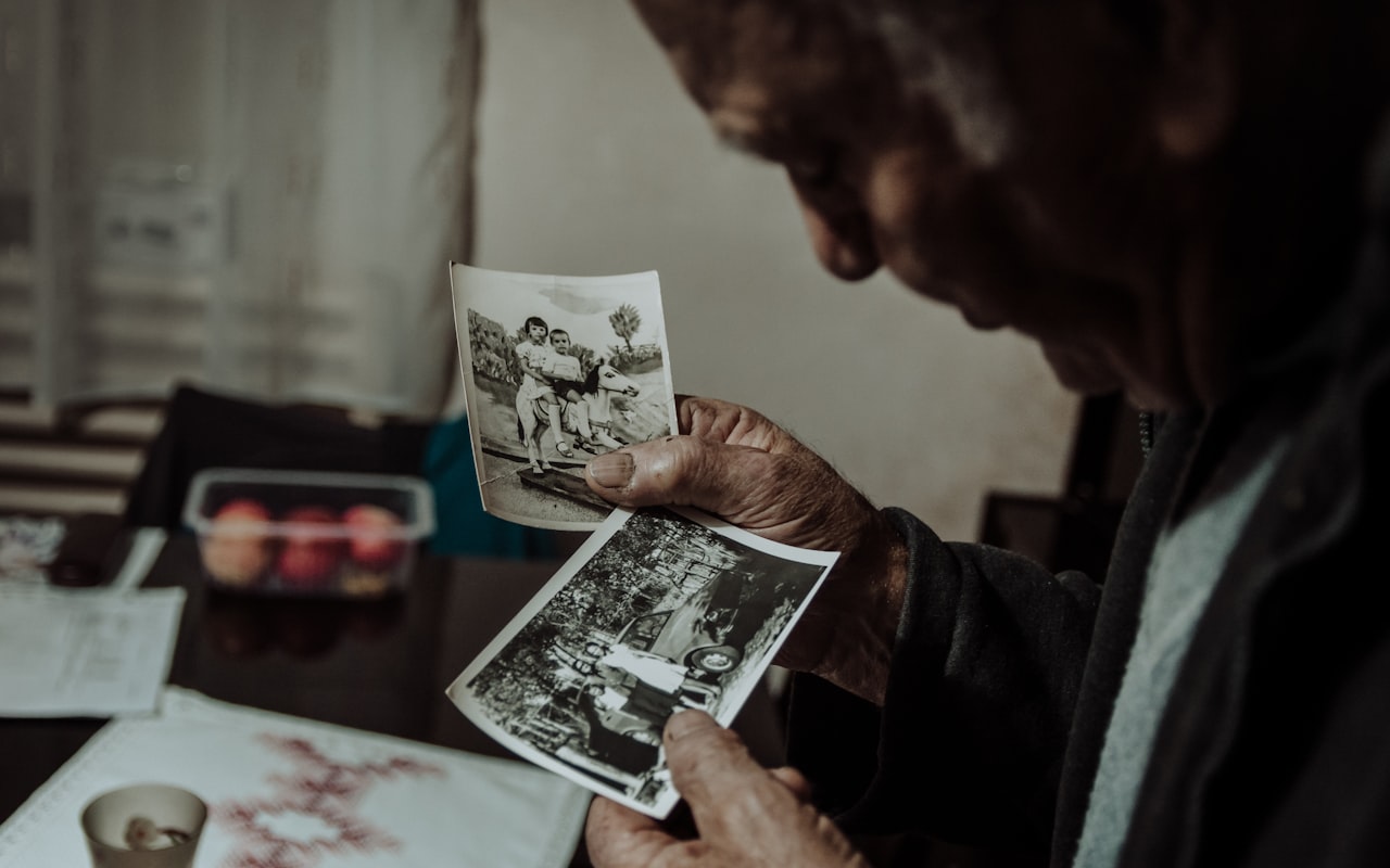Starejši moški v rokah drži dve stari črno-beli fotografiji