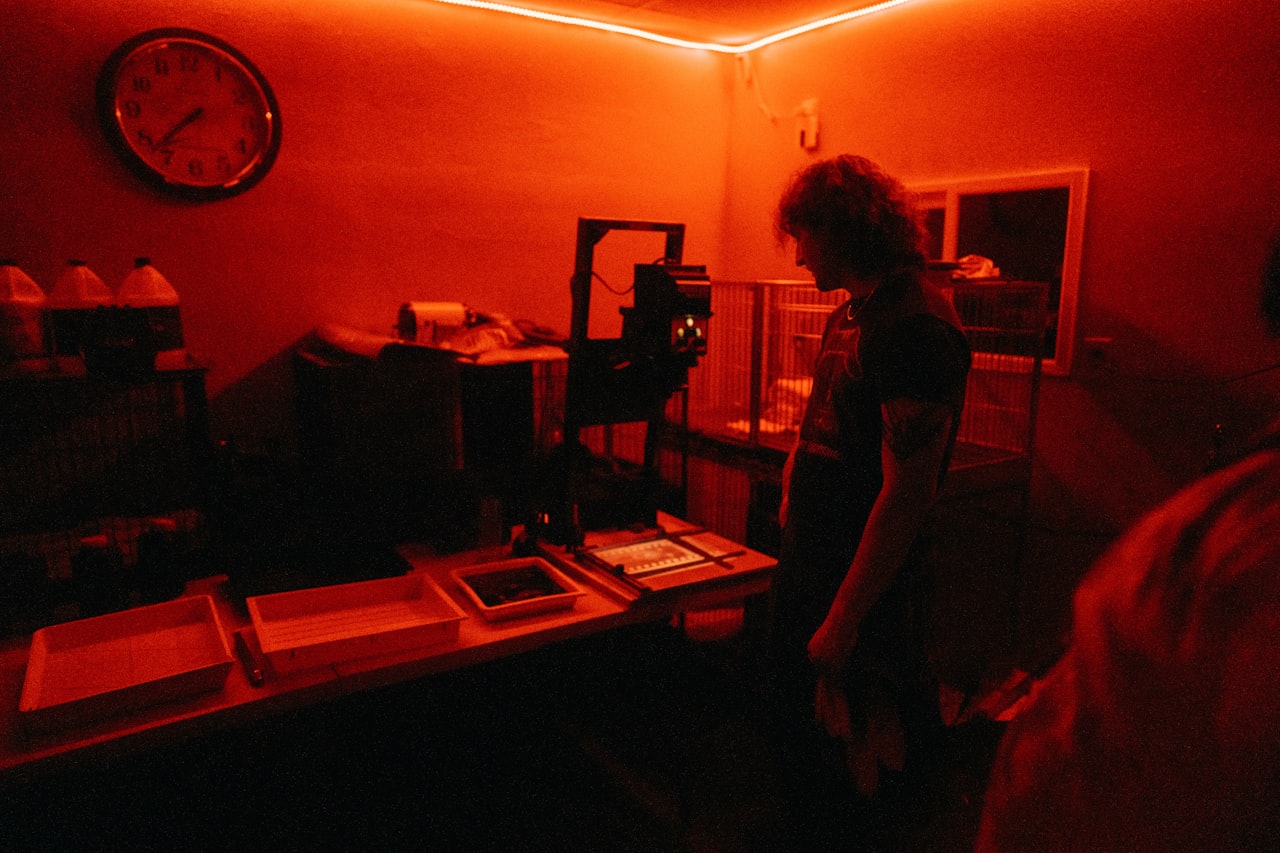 Fotograf v temnici pod rdečo lučjo med obdelavo fotografije