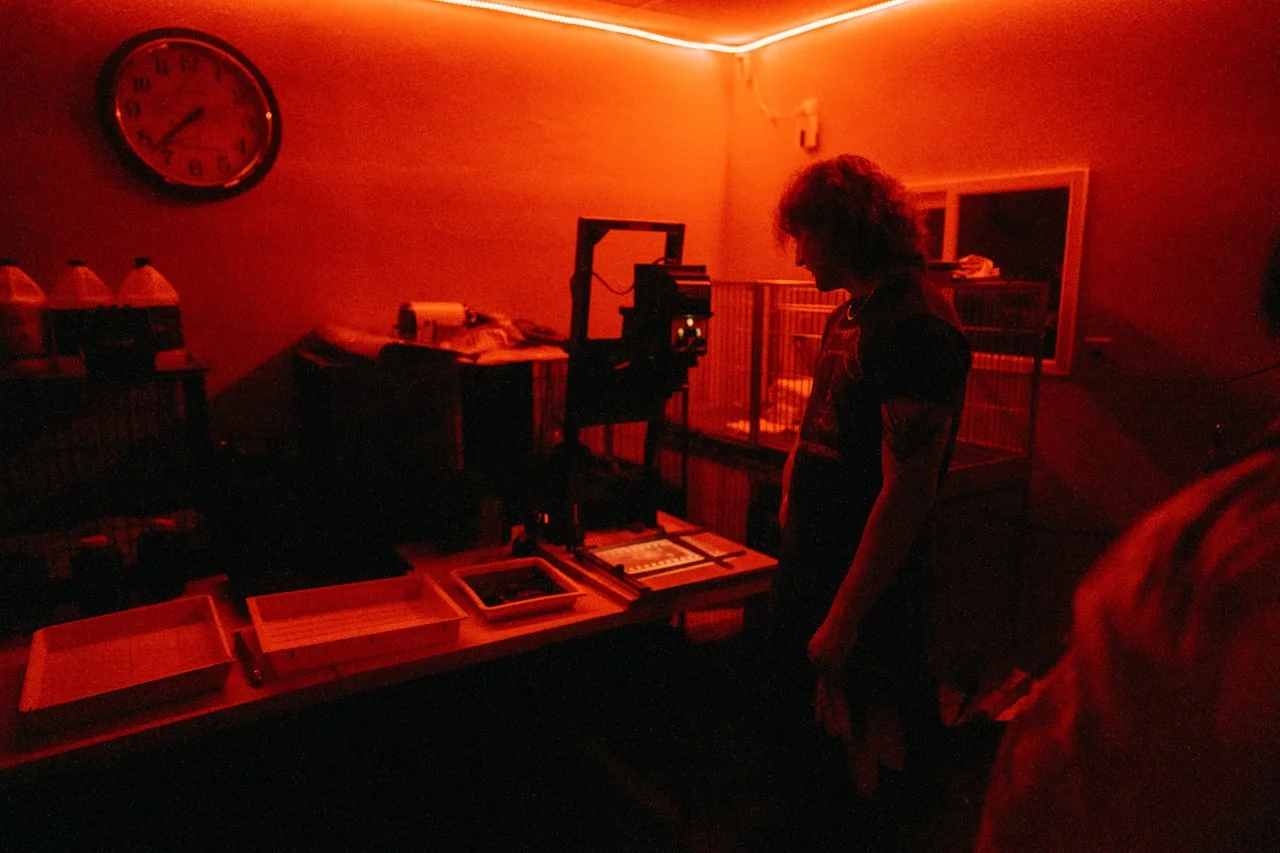 Fotograf v temnici pod rdečo lučjo med obdelavo fotografije