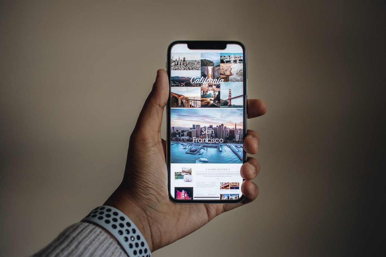 Roka, ki drži pametni telefon nad mizo s fotografijami