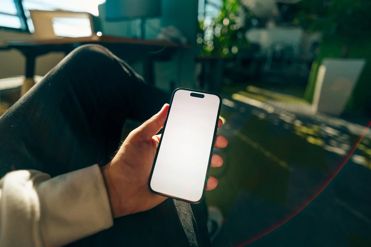 Roka drži telefon z močno svetlim zaslonom pri dnevni svetlobi