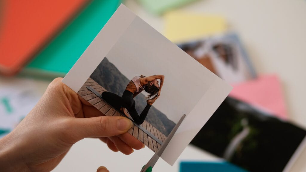 Oseba drži kakovostno natisnjeno portretno fotografijo z drugimi tiskanimi fotografijami v ozadju