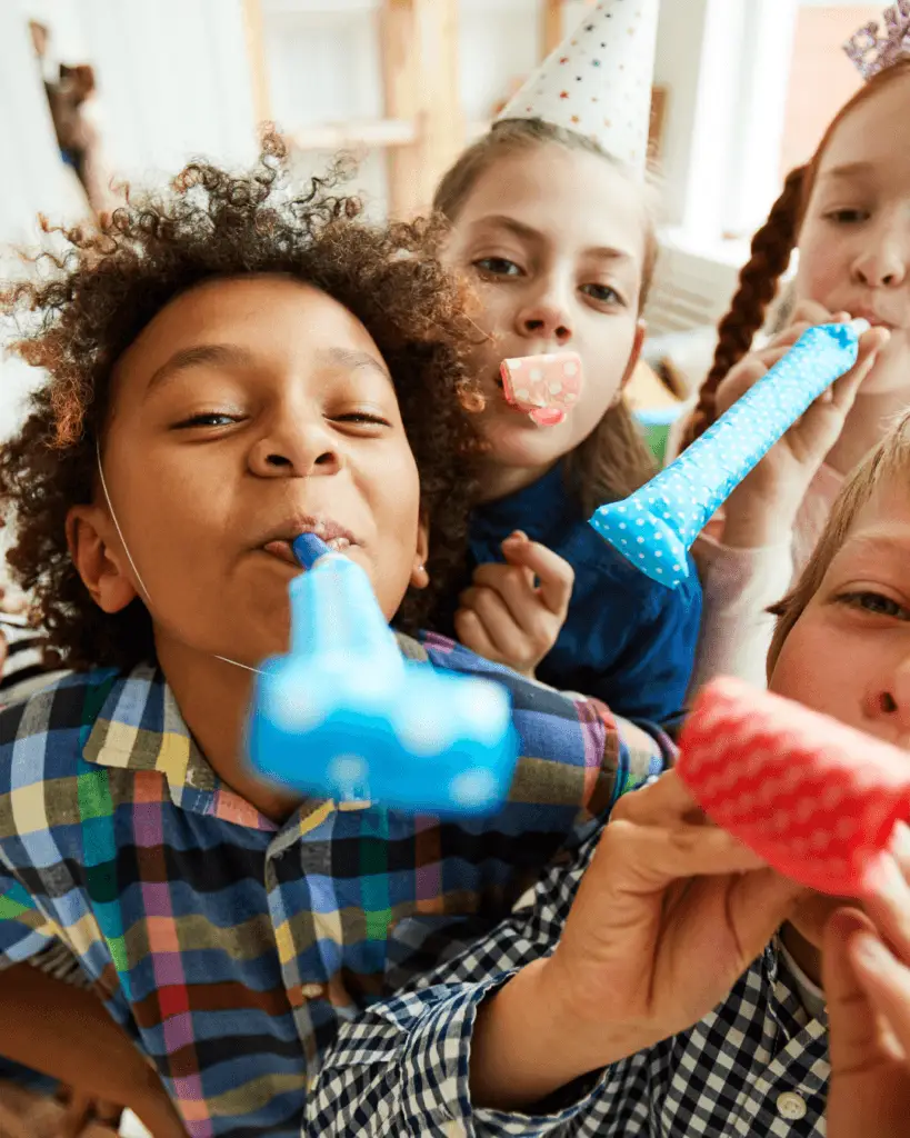 Otroci se veselijo na rojstnodnevni zabavi z barvitimi piščalkami in praznično atmosfero